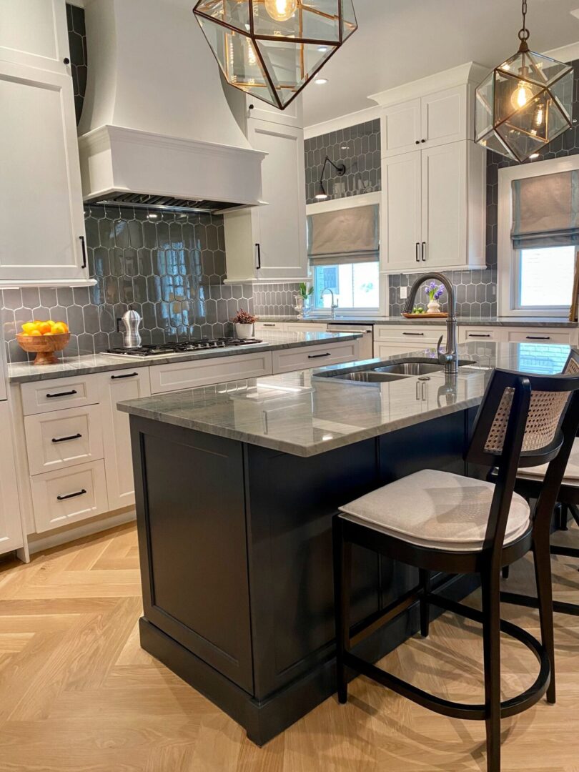 A kitchen with white cabinets and black island.