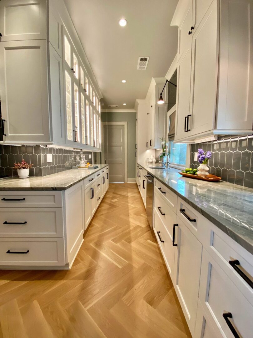 A kitchen with white cabinets and wood floors.