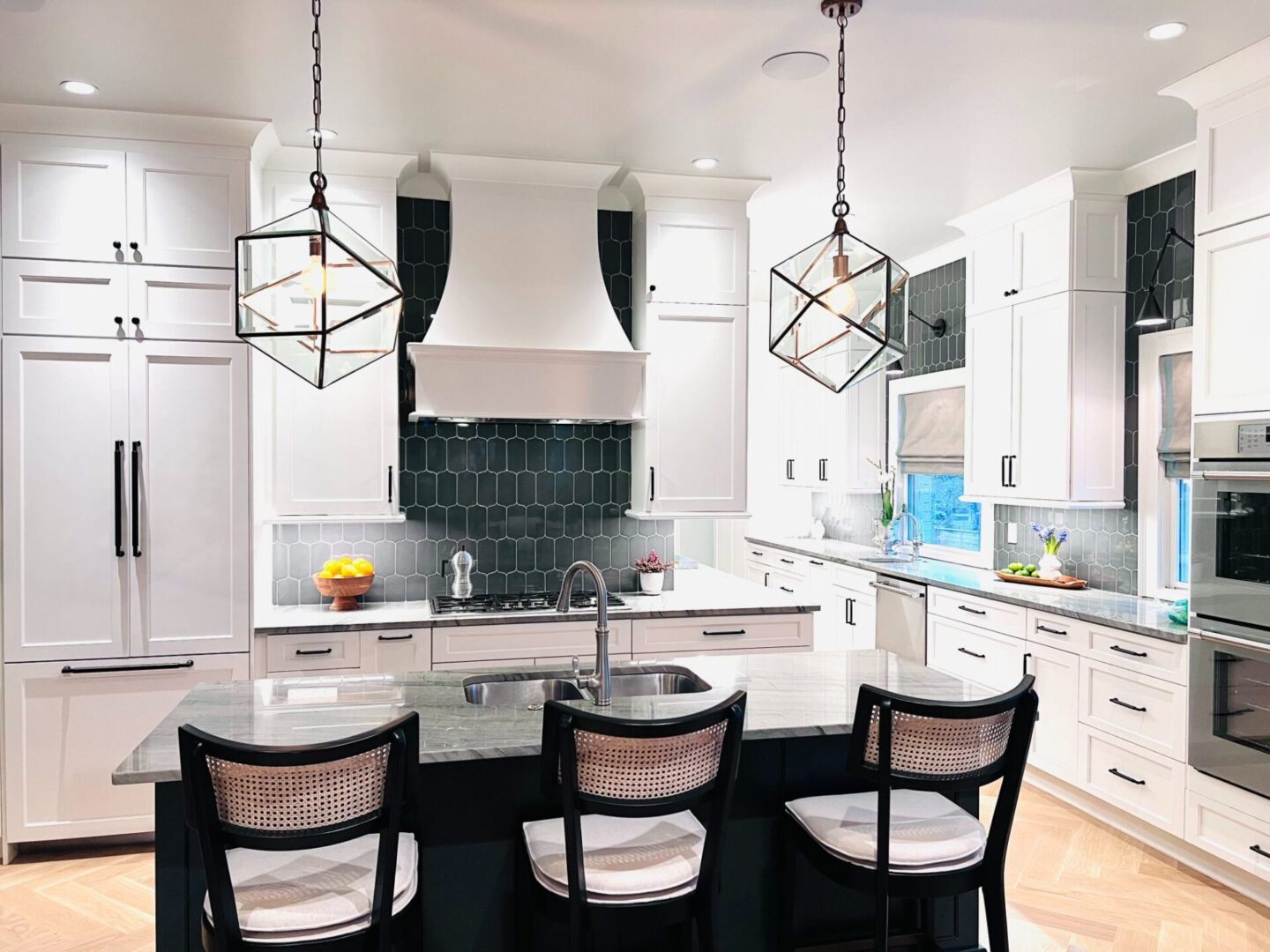 A kitchen with white cabinets and black island.