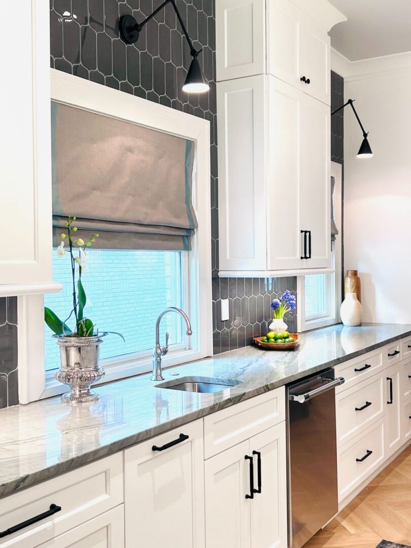 A kitchen with white cabinets and black counter tops.