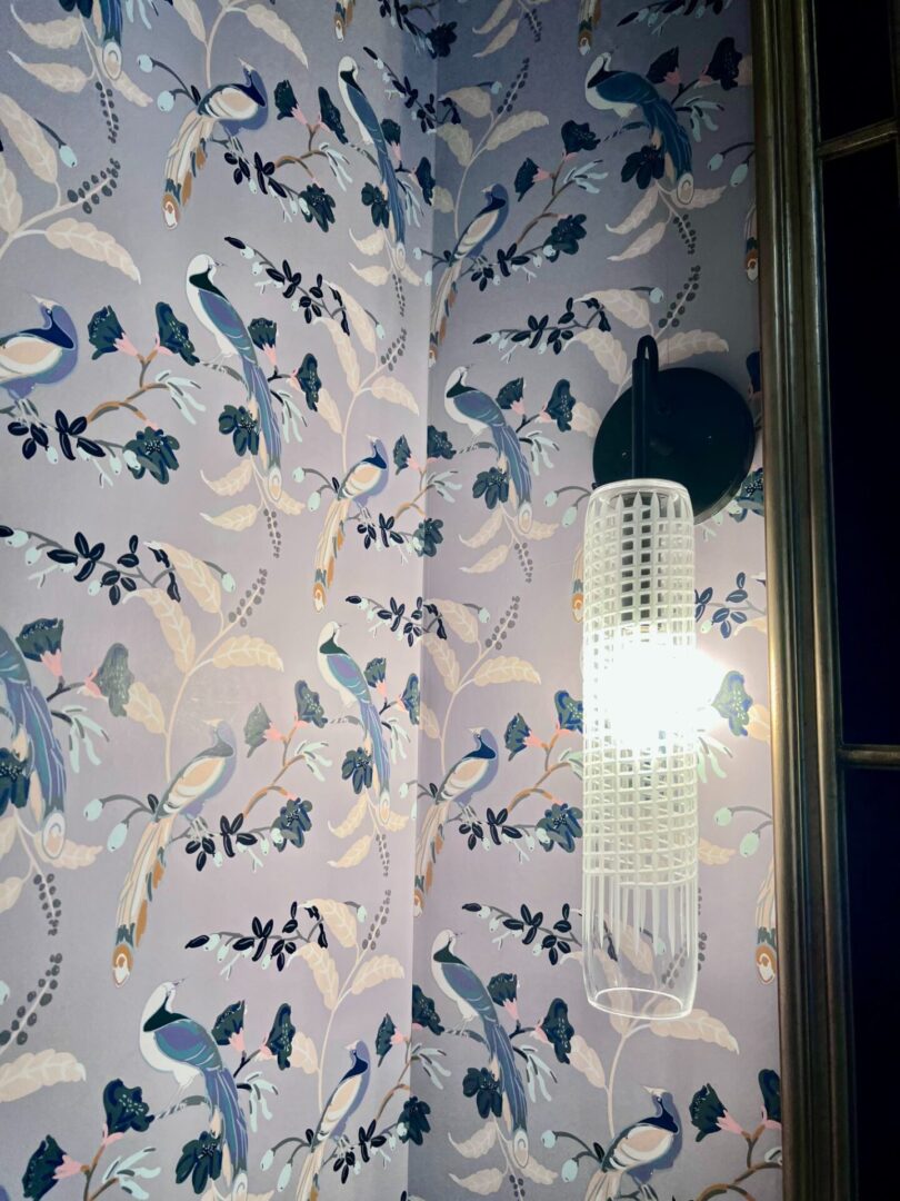 A bathroom wall with a bird wallpaper and a light