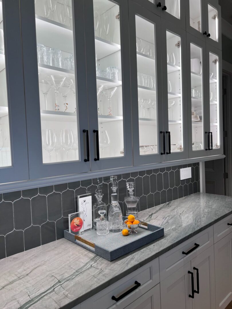 A kitchen counter with a tray of fruit and glasses.