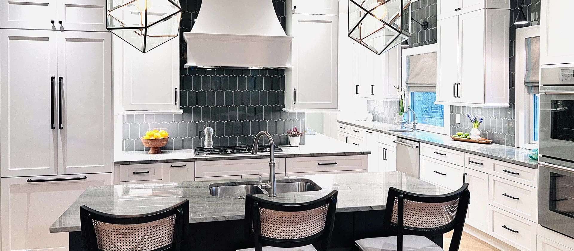 A kitchen with white cabinets and black tile.